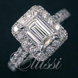 "Clio" Emerald cut diamond in a halo cluster design.